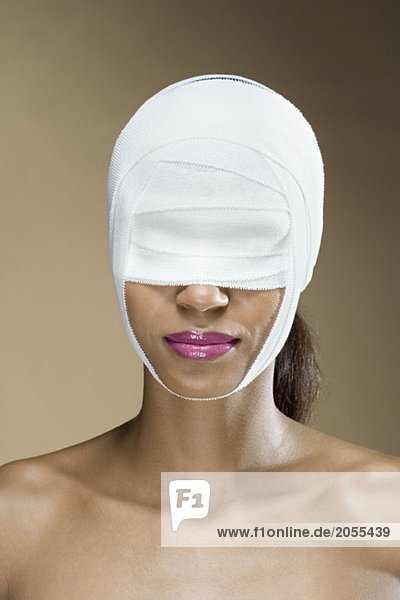 Eine Frau mit Verbänden im Gesicht.