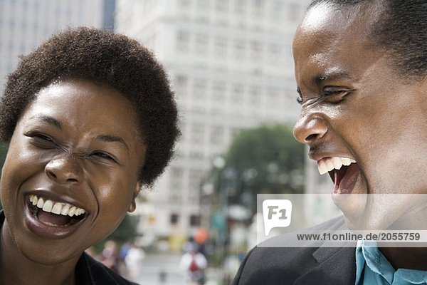 Eine Frau und ein Mann lachen zusammen draußen.