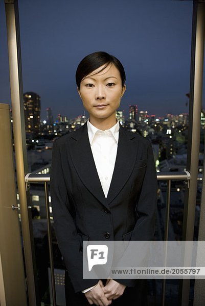 Eine Geschäftsfrau  die auf einem Balkon in Tokio steht.
