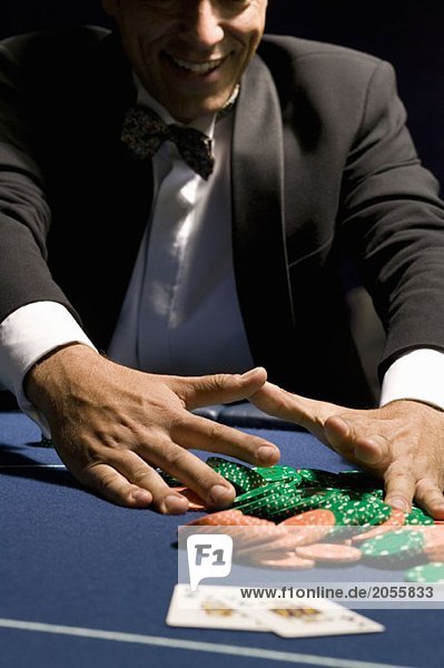 Mann sammelt seine Chips nach einem Glücksspielgewinn