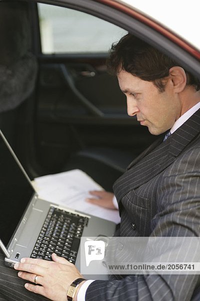 Ein englischer Geschäftsmann am Laptop in einem Taxi