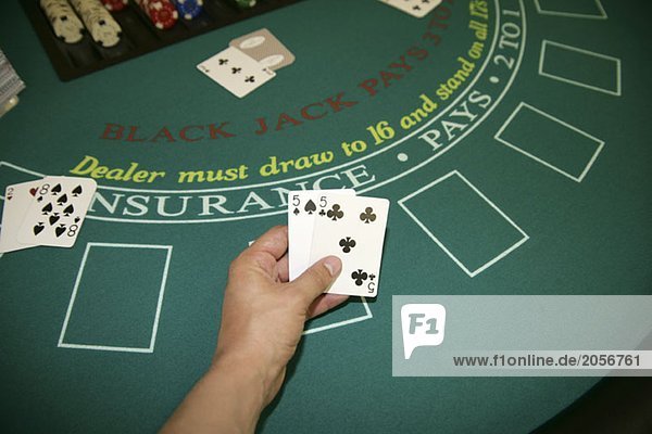 Eine Person hält Karten in der Hand an einem Blackjack-Tisch