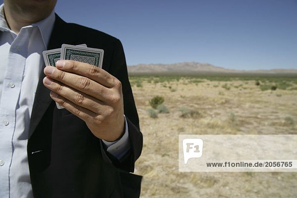 Ein Mann hält Spielkarten in der Hand in der Wüste