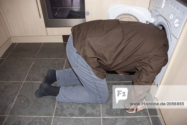 Ein Mann steckt seinen Kopf in eine Waschmaschine