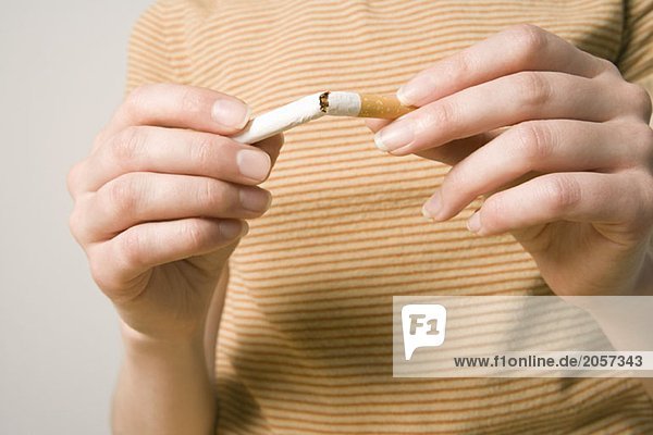 Eine Frau zerbricht eine Zigarette