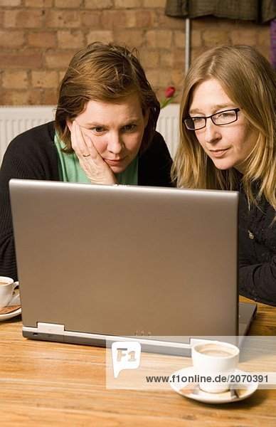 Zwei Frauen sitzen im Cafe mit Laptop