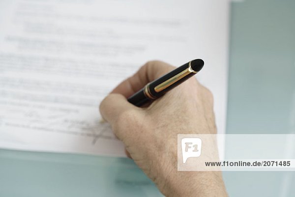 Eine Person unterschreibt Papiere/Verträge