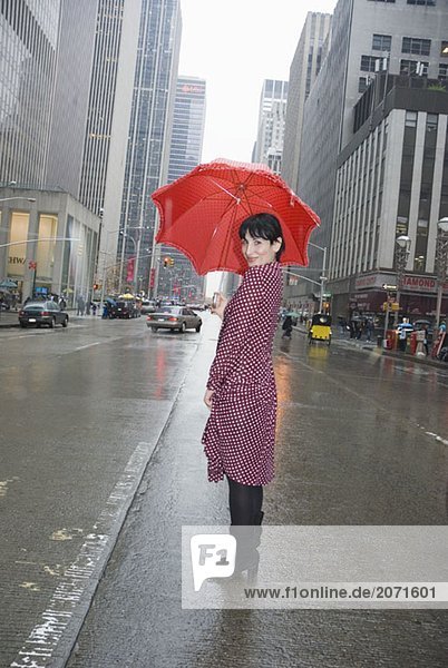 Junge Frau in einem gepunkteten Kleid mit einem gepunkteten Regenschirm auf der Straße  New York City