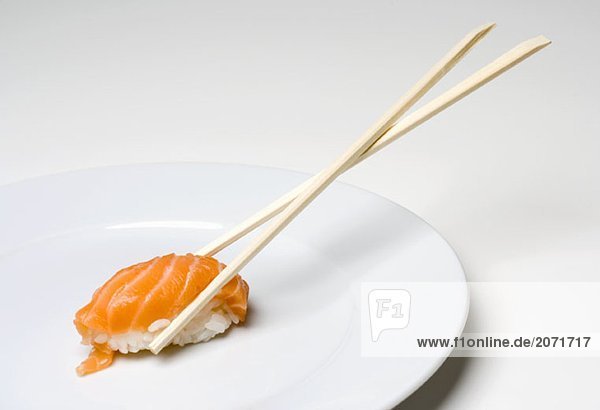 Holzessstäbchen halten ein Lach-Sushi-Stück