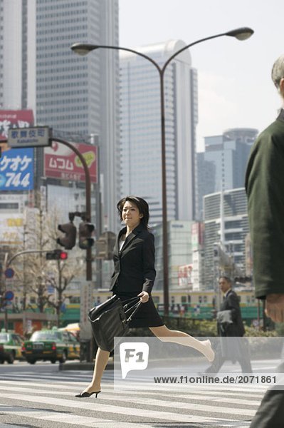 Eine junge Geschäftsfrau in der Luft beim Überqueren einer Straße  Tokio  Japan