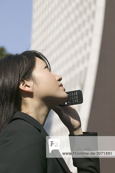 Eine junge Geschäftsfrau mit einem Mobiltelefon neben einem Wolkenkratzer