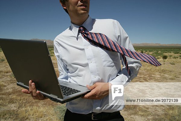 Ein Geschäftsmann mit Laptop in der Wüste