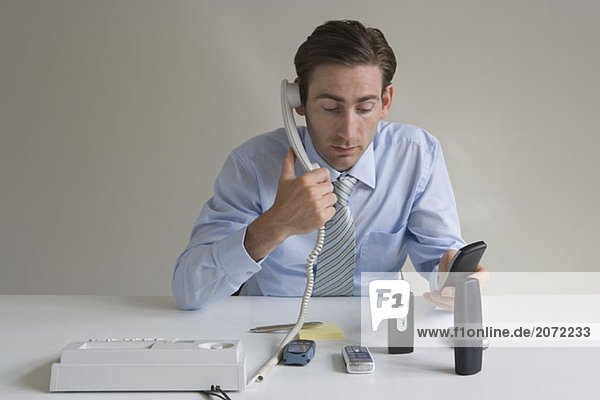 Ein Angestellter am Schreibtisch mit mehreren Telefonen