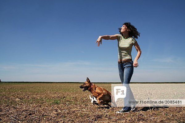 Young woman playing with dog in field