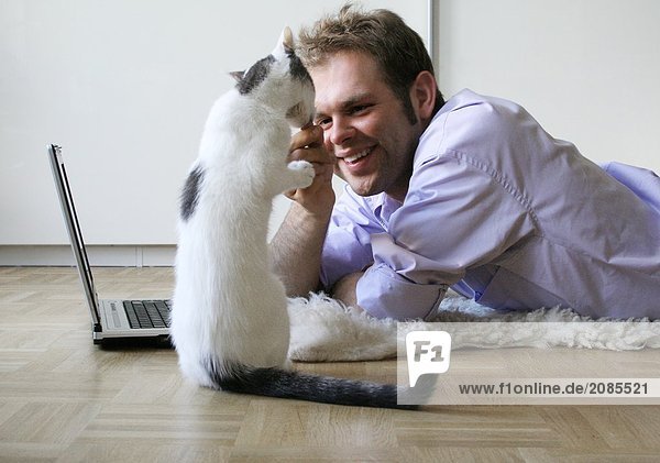 Side profile of young man feeding cat
