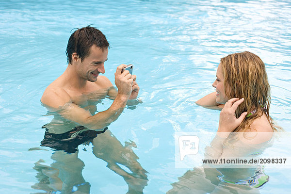 Deutschland  junger Mann fotografiert Frau im Pool