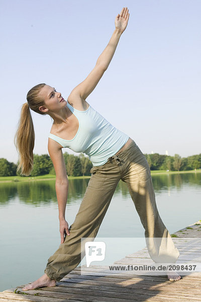 Frau (20-25) beim Yoga am Steg