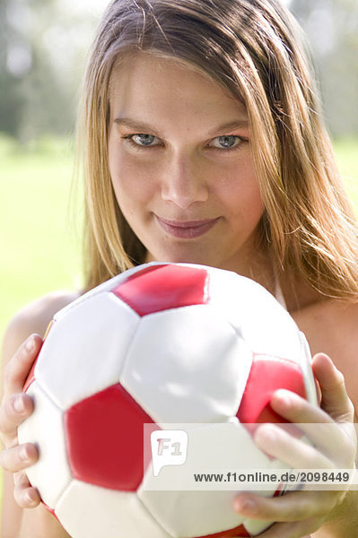Frau (20-25) hält Fußball  Portrait