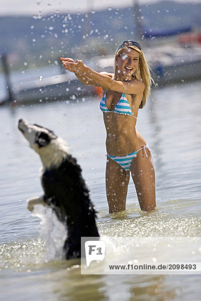 Junge Frau spielt mit Hund im See