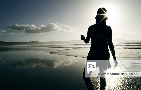 New Zealand  woman standing on beach  rear view