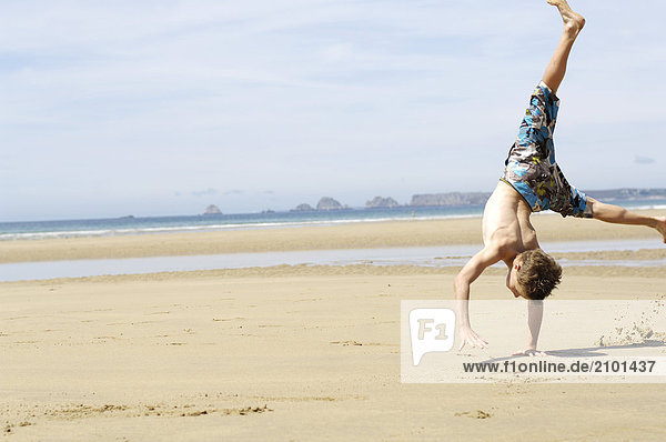Boy doing cartwheel on beach