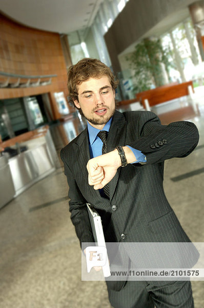 Young businessman looking at wristwatch