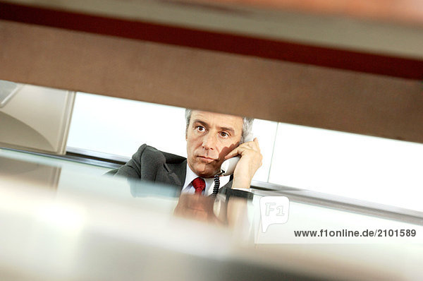Mature businessman holding telephone receiver