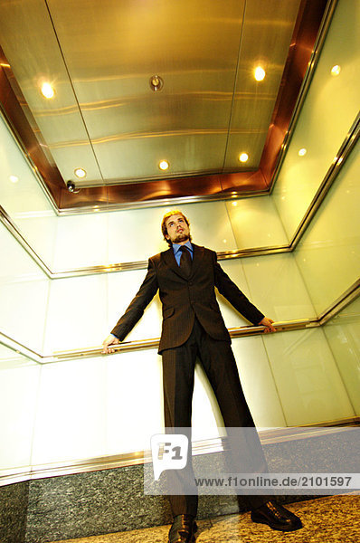 Young businessman standing in elevator  low angle view