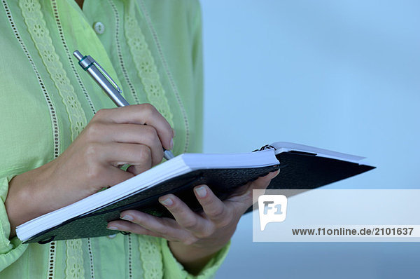 Geschäftsfrau hält Notizbuch mit Stift  Mittelteil