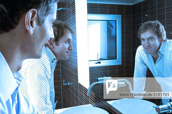 Männer schauen in den Spiegel im Waschraum  lächelnd