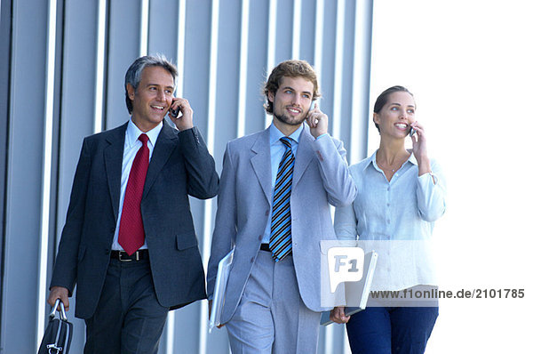Geschäftsleute  die Mobiltelefone benutzen  lächelnd