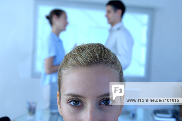 Businesswoman in office with colleagues standing in background