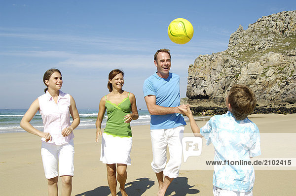 Familie spielen mit Ball am Strand