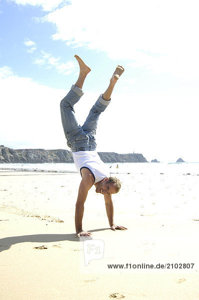 Man doing Handstand am Strand