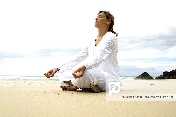 Side profile of woman meditating on beach