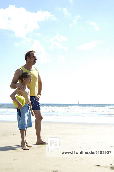 Father standing with his son on beach