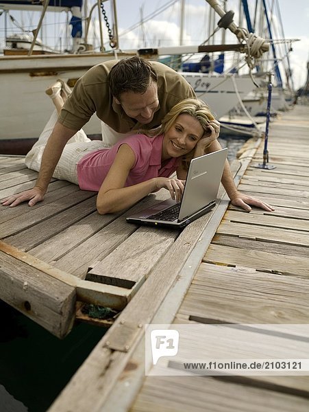 Couple looking at laptop on pier