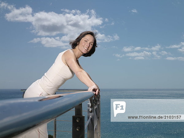 Portrait einer Frau leaning on Geländer und lächelnd