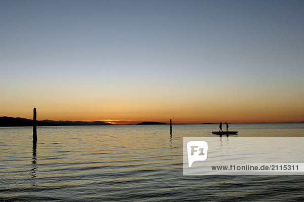 Kids in silhouette on dock against sunset  Vancouver Island  British Columba