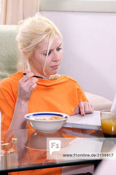 Frau mit Laptop während des Essens Getreide
