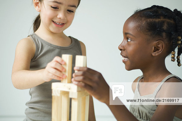 Zwei Mädchen spielen mit Bausteinen zusammen  beide lächeln