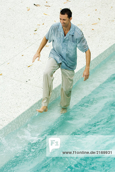Mann beim Plantschen im Pool  voll bekleidet  hohe Blickwinkel