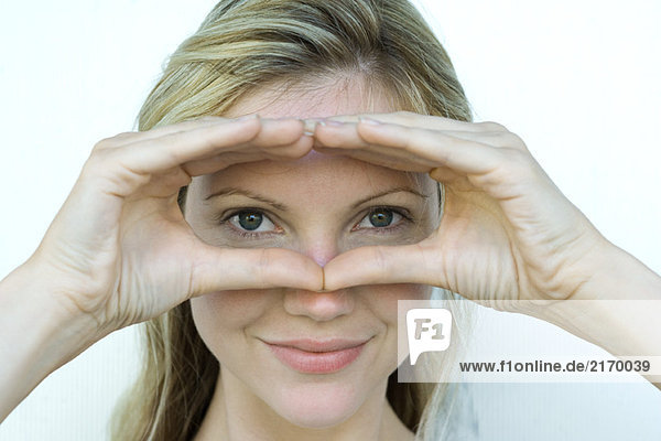 Woman looking at camera through finger frame  close-up