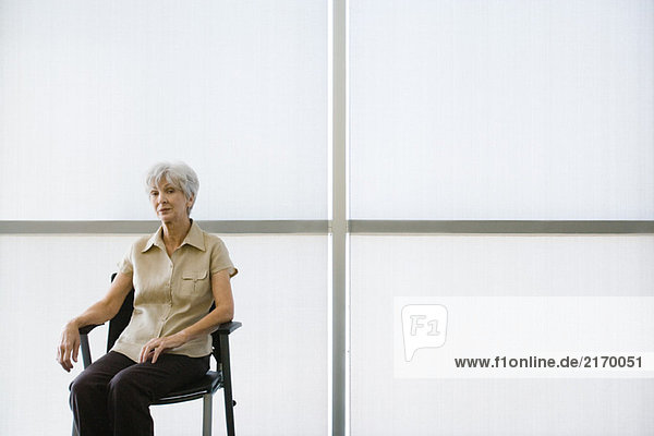 Seniorin auf dem Stuhl sitzend mit Blick auf die Kamera