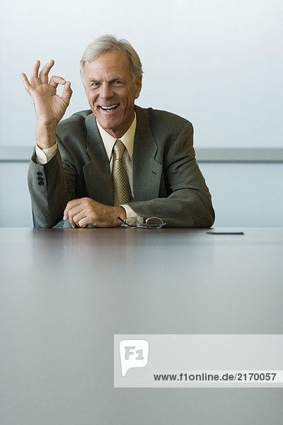 Businessman making OK hand gesture and smiling at camera