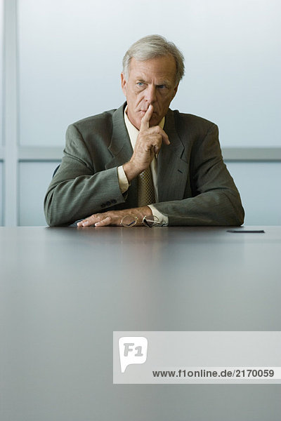 Businessman holding finger to lips  looking away