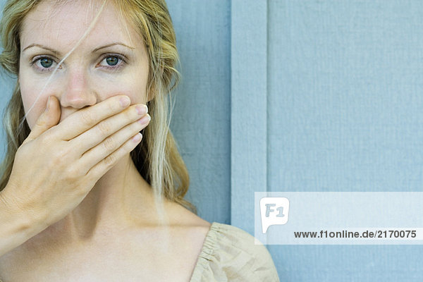 Woman covering mouth with hand  looking at camera