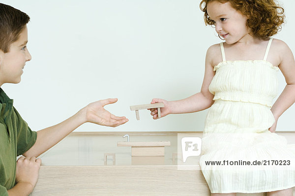 Junge und kleine Schwester spielen mit Blöcken  Mädchen übergibt Stück an Bruder