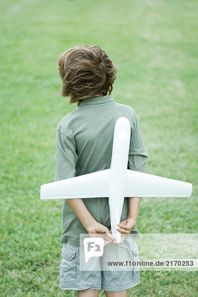Junge hält Spielzeugflugzeug hinter dem Rücken  Rückansicht