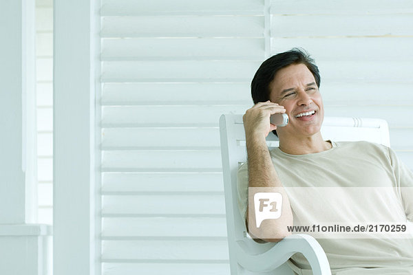 Mann mit Handy auf der Veranda  lächelnd
